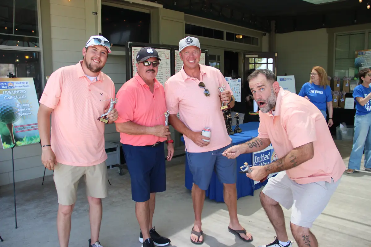Men's team winners celebrate with trophies during the Live United Golf Classic awards ceremony